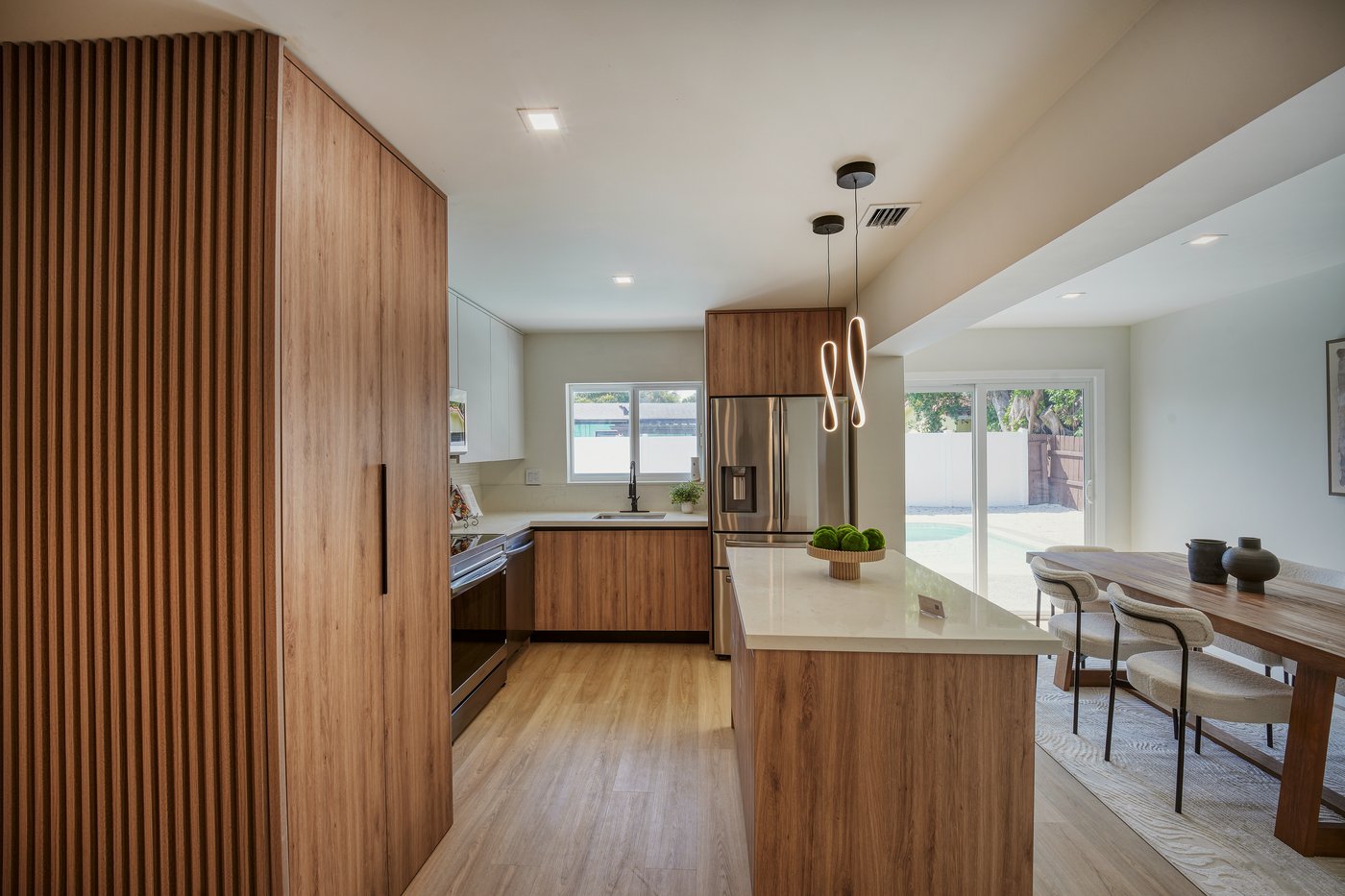 Kitchen with white quartz island, walnut cabinets and sculptural pendant lights