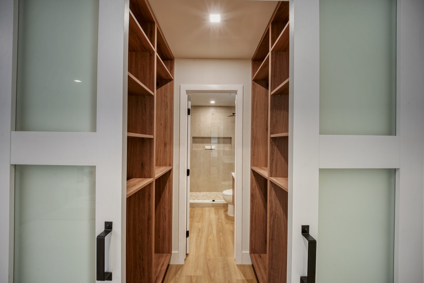 Walk-in wardrobe with floor-to-ceiling walnut shelving on both sides
