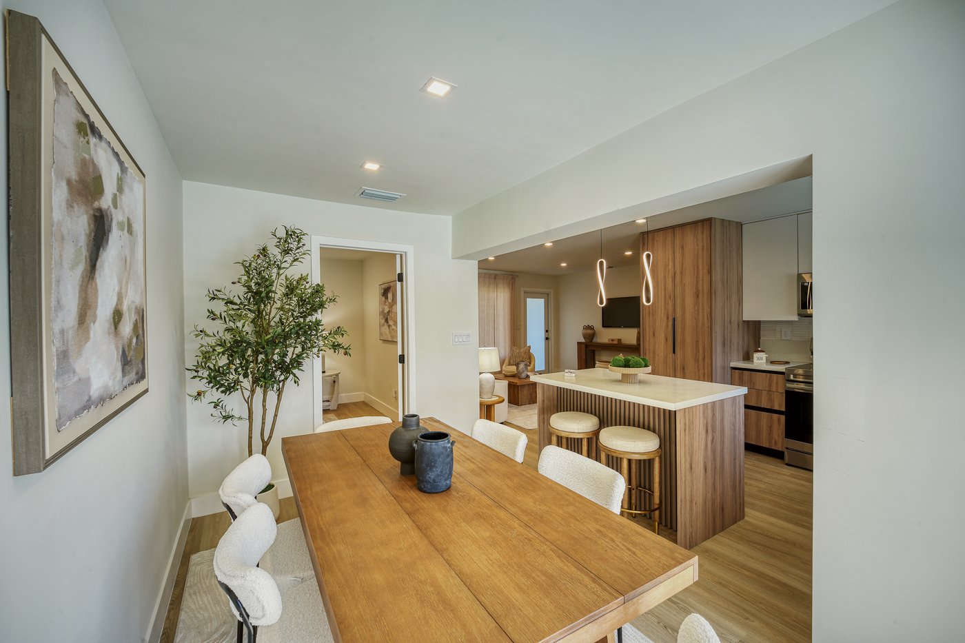 Dining room with a long wood table and a view through to the kitchen